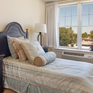 A cozy bedroom with a single bed and large window allowing natural light.
