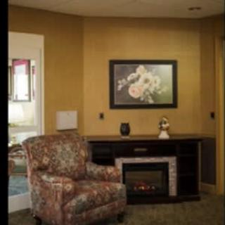 A cozy living room corner with an armchair, fireplace, and wall art.