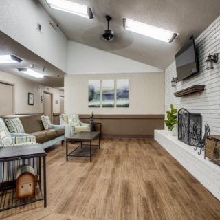 A modern living room with wooden flooring, a fireplace, and a wall-mounted television.
