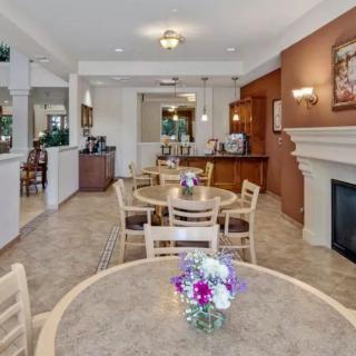 A cozy cafe interior with round tables, chairs, and colorful flower centerpieces near a fireplace.