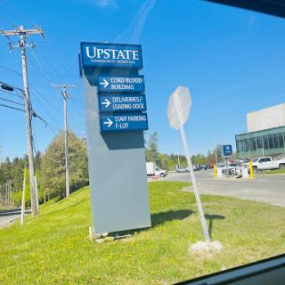 Directional sign for Upstate facilities on a sunny day.