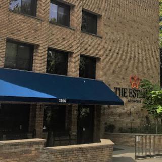 A modern brick building with a blue awning at the entrance.