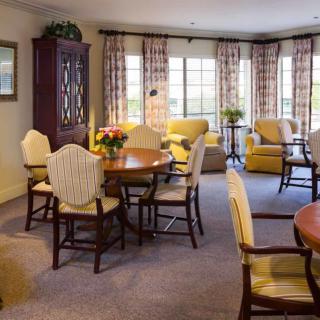 A cozy living room with a dining area, featuring elegant furniture and large windows.
