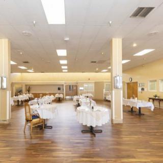 An empty dining area with neatly arranged tables and chairs on a wooden floor.