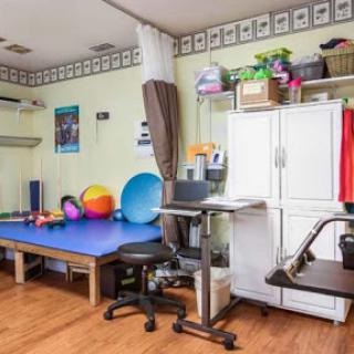 A well-equipped therapy room featuring exercise balls, a treatment table, and a workspace.