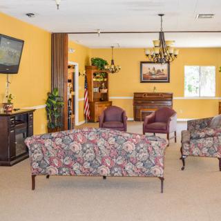 A cozy living room with floral-patterned sofas, a television, and a chandelier.