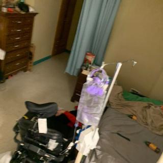 A bedroom with a wheelchair and medical equipment near the bed.