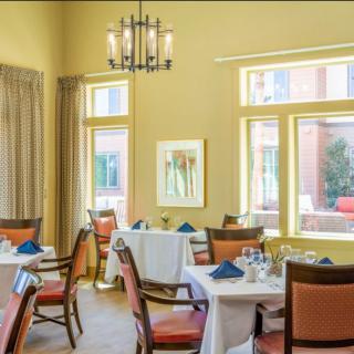 Elegant dining room with neatly arranged tables and chairs, featuring large windows and soft lighting.