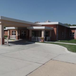 A brick building with a covered entrance and driveway on a sunny day.