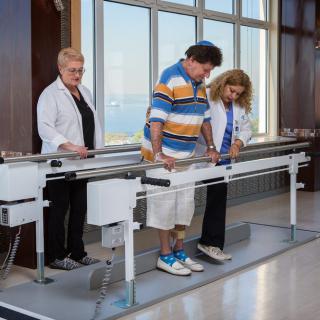 A patient undergoing physical therapy with the assistance of two therapists in a medical facility.