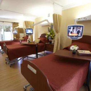 A hospital room with multiple beds equipped with personal televisions.