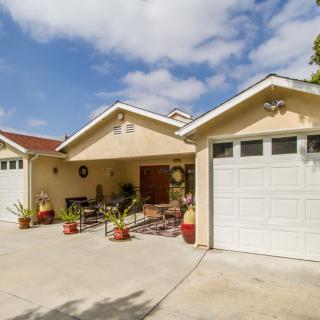 A suburban house with a driveway and garage under a partly cloudy sky.
