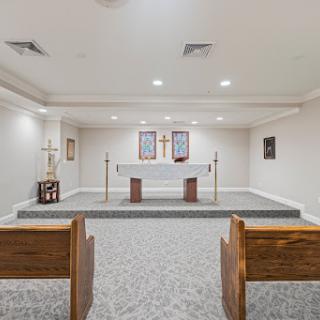 A serene chapel space featuring a central altar with wooden pews for worship.