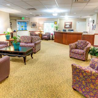 A cozy lobby area with patterned chairs and a reception desk in the background.