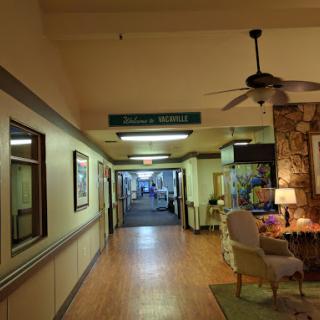 A view of a well-lit hallway in a healthcare facility, featuring comfortable seating and decor.