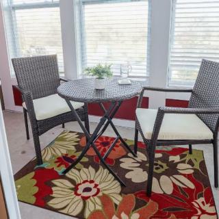A cozy indoor seating area with a small round table, two chairs, and a colorful floral rug.