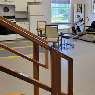 A spacious therapy room featuring a kitchenette, exercise equipment, and comfortable seating arrangements.