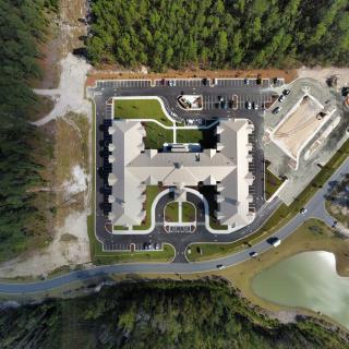 Aerial view of a building complex surrounded by trees and parking lots.
