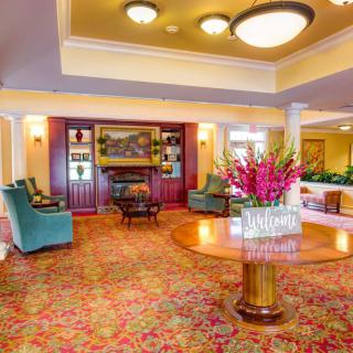 A spacious and elegantly decorated lobby featuring comfortable seating, vibrant floral arrangements, and warm lighting.