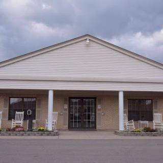 A welcoming building with a porch and large windows under a cloudy sky.