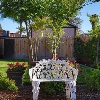 A peaceful garden setting with a decorative white bench amidst lush greenery and colorful flowers.