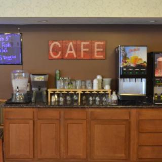 Self-serve cafe area with various drink dispensers and glasses on display.