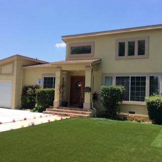 A suburban two-story house with a well-maintained lawn and large windows.