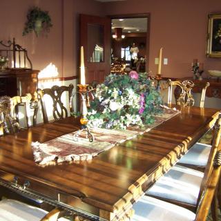A well-decorated dining room with a large wooden table and elegant chairs, featuring a floral centerpiece.