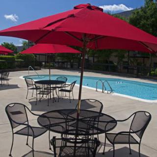 A peaceful outdoor area featuring a swimming pool and patio furniture with red umbrellas.