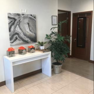 An office interior with a table displaying decor items and a painting on the wall.