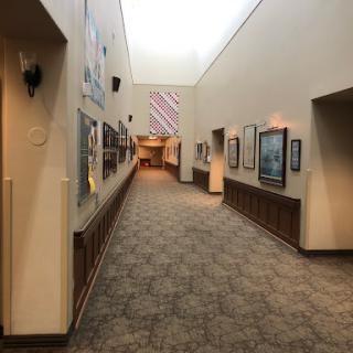 A well-lit hallway showcasing various art pieces along the walls.