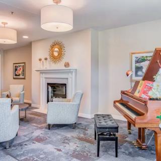 A cozy living room featuring a piano, comfortable seating, and a fireplace.