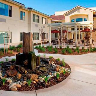 A beautifully landscaped courtyard with a fountain in front of a modern building.