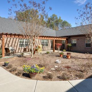 A sunny courtyard garden with surrounding brick buildings and a pathway.