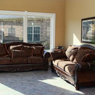 A cozy living room featuring a brown couch and loveseat set by a large window allowing natural light to fill the space.