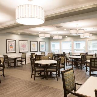 A spacious and well-lit dining area with multiple tables and chairs, decorated with framed art on the walls.