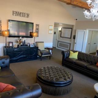 A modern living room with leather sofas, a large ottoman, and a wall-mounted television.