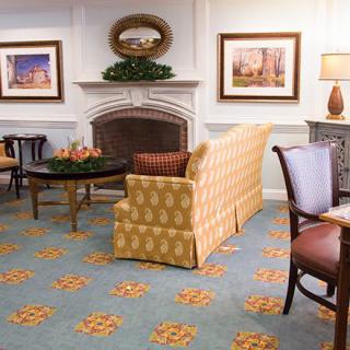 A cozy living room with a patterned sofa, elegant fireplace, and decorative artwork on the walls.
