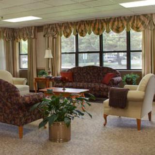 A cozy living room with elegant furniture, large windows, and potted plants.