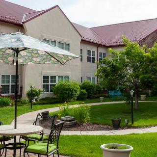A well-maintained courtyard with patio furniture and lush greenery in front of a residential building.