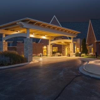 A well-lit building entrance at night with a covered driveway.