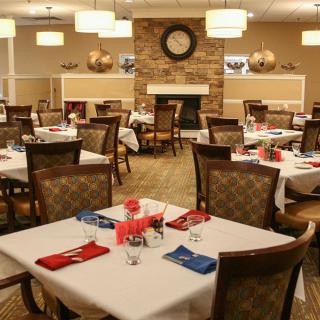 A cozy restaurant dining area with neatly arranged tables and chairs, featuring warm lighting and tasteful decor.