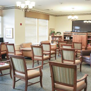 A well-lit waiting room with multiple chairs, a television, and a bookshelf.