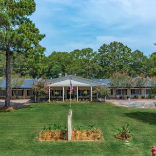 A scenic view of a residential building surrounded by well-maintained gardens and trees.