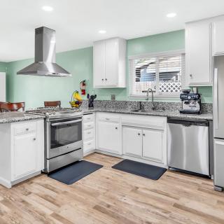 A modern kitchen featuring white cabinets, stainless steel appliances, and hardwood floors.