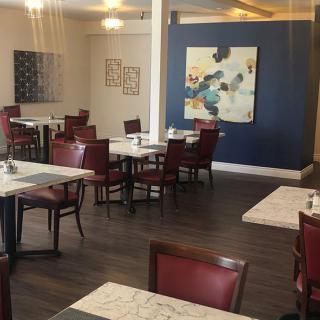 A modern restaurant interior with tables and chairs, adorned with artwork on the walls.
