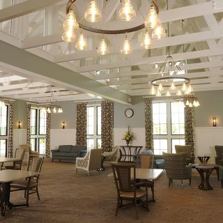 A well-lit dining area with chandeliers, tables, and chairs arranged for comfortable seating.
