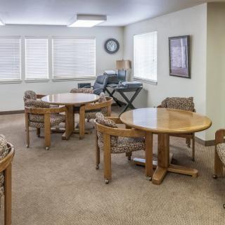 A well-lit meeting room with round tables and chairs, featuring a piano keyboard in the corner.