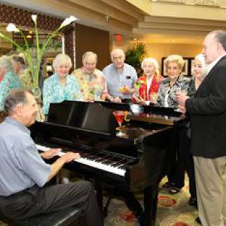 A group of people gathered around a piano enjoying music and celebrating together.