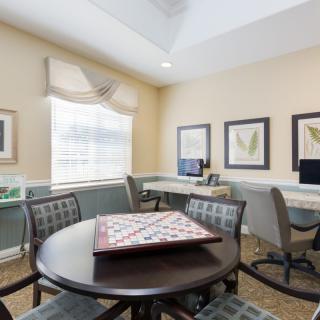 A bright office space with a round table, computers, and framed artwork on the walls.
